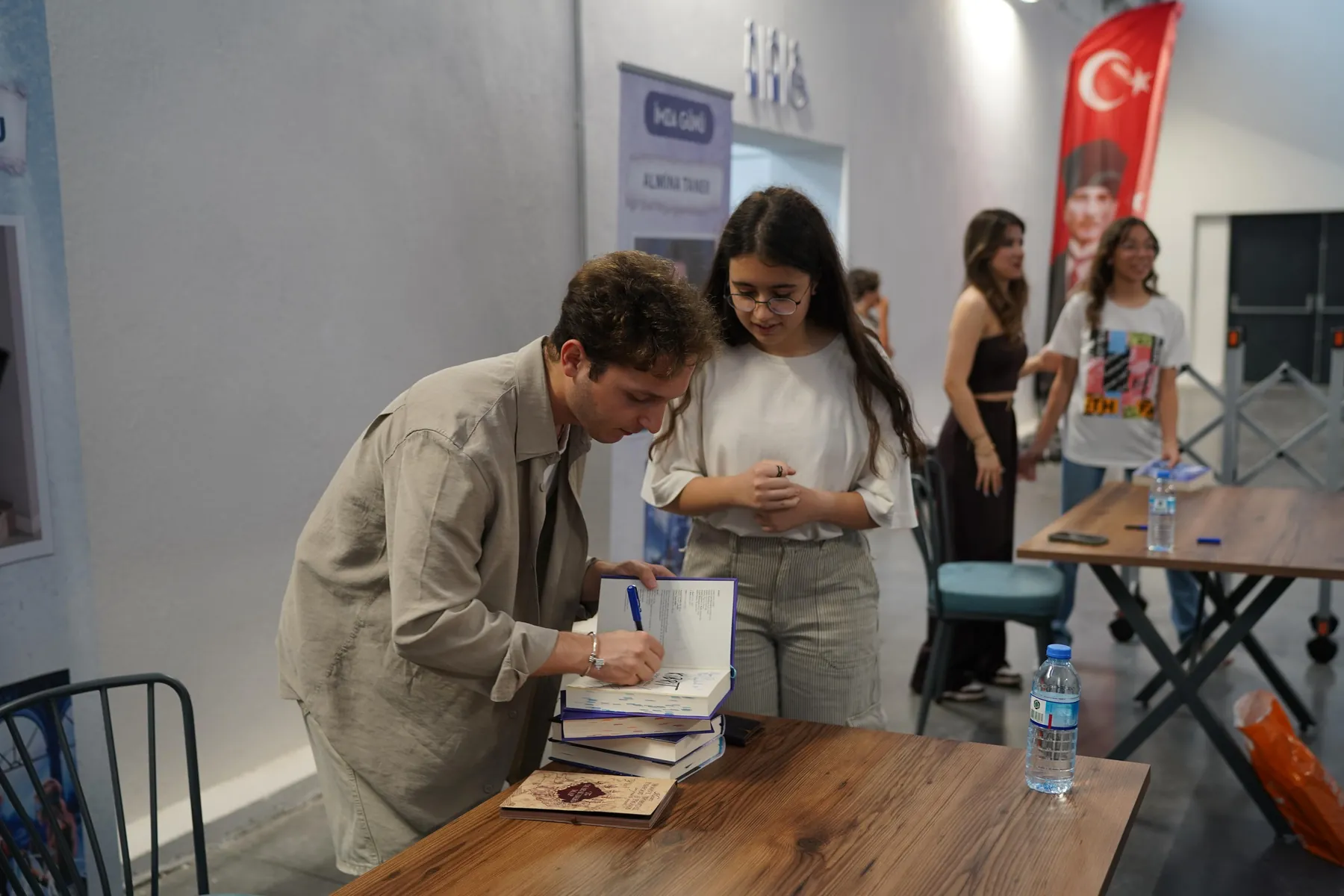 Bir yazarın imza masasında okurun kitabını imzalaması