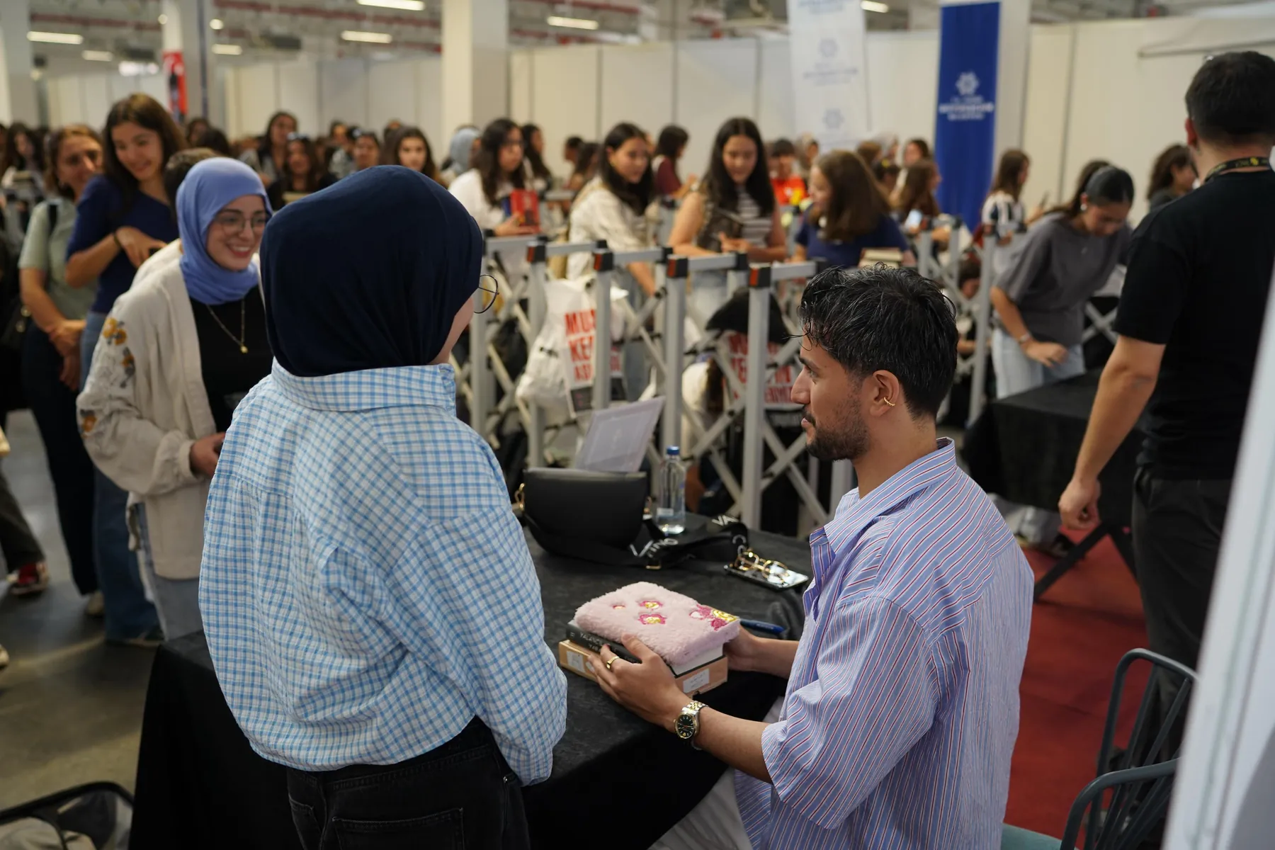 Bir stantta elinde kitap tutup inceleyen ziyaretçiler